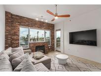 Inviting living room featuring a brick fireplace, modern ceiling fan, and large windows for ample natural light at 2302 N Central Ave # 206, Phoenix, AZ 85004