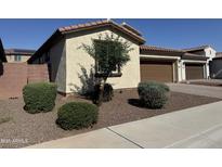 Charming single-story home featuring desert landscaping, a brown garage door, and a tile roof at 7046 N 84Th Dr, Glendale, AZ 85305