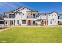 New townhome with manicured lawn, balcony, and modern white facade against a clear blue sky at 11300 N Casa Dega Dr # 1090, Surprise, AZ 85388