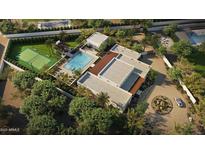 Expansive property with a pool, tennis court, and modern architecture surrounded by mature trees and landscaping at 13202 N 76Th Pl, Scottsdale, AZ 85260