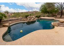 Backyard pool features a rock waterfall, desert landscaping and mountain views at 18359 W Sweet Acacia Dr, Goodyear, AZ 85338