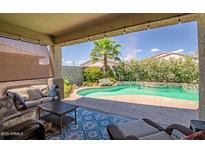 Inviting outdoor living space with covered patio and sparkling pool surrounded by lush landscaping at 18662 W Foothill Dr, Surprise, AZ 85387