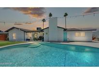 Tranquil backyard showcasing a sparkling pool, lush greenery, and an inviting outdoor living space at sunset at 2820 E Surrey Ave, Phoenix, AZ 85032