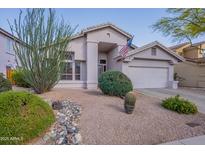 Charming single-story home featuring desert landscaping, an attached two-car garage, and an American flag at 31017 N 41St Pl, Cave Creek, AZ 85331