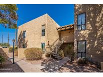 Charming condo exterior with stone facade, stairway, and desert landscaping under a clear blue sky at 4950 N Miller Rd # 233, Scottsdale, AZ 85251