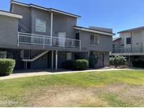 Low-rise apartment building with dark gray exterior, second story balconies and green lawn at 19601 N 7Th St Ave # 1036, Phoenix, AZ 85024