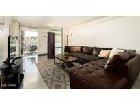 Comfortable living room features a leather sofa, neutral walls, and a view to the home's entrance at 6936 E 4Th St # 5, Scottsdale, AZ 85251