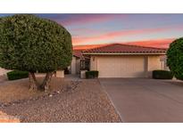 Charming home with a two-car garage, desert landscaping, and a red tile roof in front of a colorful sunset at 9809 W Behrend Dr, Peoria, AZ 85382