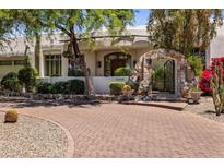 Front exterior of home with brick driveway, stone entry, and lush landscaping at 11717 E Estrella Ave, Scottsdale, AZ 85259