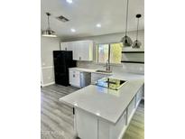 This updated kitchen features gray-tone wood floors, white cabinetry, and a modern island cooktop at 2138 E Williams Dr, Phoenix, AZ 85024