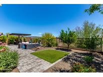 Inviting backyard featuring a pergola, stylish furniture, lush plants, and a small patch of artificial grass at 29403 N 119Th Ln, Peoria, AZ 85383