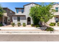 Charming two-story home featuring a textured facade, arched entryway, and well-maintained desert landscaping at 302 N 69Th Pl, Mesa, AZ 85207