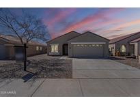 Charming single story home with desert landscaping, a two car garage, and lovely sunset sky at 16077 W Larkspur Dr, Goodyear, AZ 85338