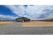 Gravel driveway leading to a house with desert landscaping and clear skies in the background at 20427 W Mountain Sage Dr, Buckeye, AZ 85326