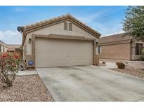 Beige two-car garage with a concrete driveway and low maintenance desert landscaping at 24009 W Antelope Trl, Buckeye, AZ 85326