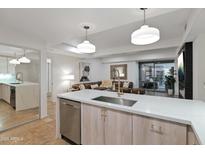 Modern kitchen featuring stone countertops, stainless steel appliances, and pendant lighting, seamlessly flowing into the living area at 7137 E Rancho Vista Dr # 3007, Scottsdale, AZ 85251