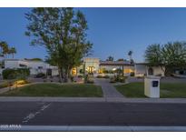 Elegant exterior elevation with a brick walkway, manicured lawn, and desert landscaping at dusk at 7471 E Northern Ave, Scottsdale, AZ 85258