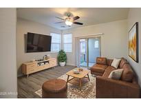 Bright living room featuring a modern sofa, a ceiling fan, and a sliding glass door at 1624 N 77Th Gln, Phoenix, AZ 85035