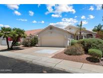 Charming single-story home with a two-car garage, mature landscaping, and a tile roof, set against a beautiful blue sky at 21675 N 61St Ave, Glendale, AZ 85308