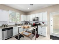 Modern kitchen featuring white cabinets, stainless steel appliances, and a movable island at 2543 N 73Rd Dr, Phoenix, AZ 85035