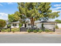 Charming single-story home with a well-manicured front yard, black fence and lush landscaping at 3308 N 51St St, Phoenix, AZ 85018