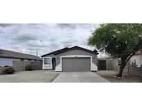 Charming home featuring a two-car garage, desert landscaping, and a cozy covered entry at 719 E Broadway Ave, Apache Junction, AZ 85119