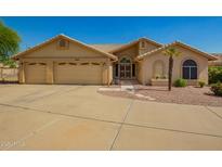 Charming tan home featuring a three-car garage and desert landscaping at 8627 W Morrow Dr, Peoria, AZ 85382