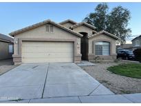 Charming single-story home with a two-car garage and desert landscaping under a clear sky at 10649 W Alvarado Rd, Avondale, AZ 85392