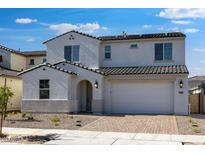 Inviting two-story home with a charming stucco facade, paver driveway, and a well-manicured front yard at 16810 W Yucatan Dr, Surprise, AZ 85388