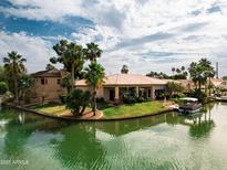 Waterfront home with tile roof, lush landscaping, and a boat dock for enjoying the serene lake at 2128 E Clipper Ln, Gilbert, AZ 85234
