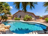Inviting pool with beautiful landscaping, set in a well-maintained backyard oasis with mature palms at 35654 N Vidlak Dr, San Tan Valley, AZ 85143