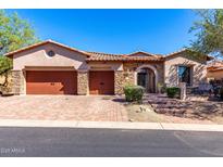 Charming single-story home with stone accents, a tile roof, a three-car garage, and attractive desert landscaping at 7939 E Stonecliff Cir, Mesa, AZ 85207
