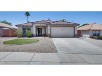 Charming single-story home with desert landscaping, a tiled roof, and a two-car garage at 10557 W Louise Dr, Peoria, AZ 85383