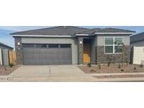 Charming single-story home featuring a gray exterior, gray garage door, and low maintenance landscaping at 25235 N 183Rd Dr, Wittmann, AZ 85361