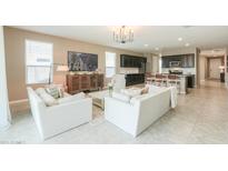 Open-concept living room with tile floors, neutral walls, and view into the modern kitchen at 37903 W San Clemente St, Maricopa, AZ 85138