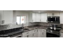 Modern kitchen featuring white cabinets, stainless steel appliances, and granite countertops at 2721 E Beverly Ln, Phoenix, AZ 85032