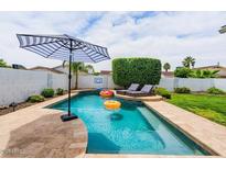 Refreshing pool with patio, loungers, umbrella, and lush landscaping perfect for outdoor relaxation and fun at 605 W Sandra Ter, Phoenix, AZ 85023