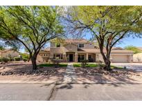 Two-story home with a landscaped front yard and mature trees in a desert landscape at 9998 W Prospector Dr, Queen Creek, AZ 85144