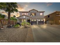 Charming two-story home showcasing a well-manicured desert landscape, palm trees and a three car garage at 14878 W Windrose Dr, Surprise, AZ 85379