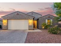 Charming single-story home featuring a stucco exterior and a two-car garage at dusk at 18630 W Lawrence Ln, Waddell, AZ 85355