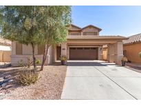 Inviting tan two-story home featuring a covered two-car driveway, desert landscaping, and a neutral color scheme at 44859 W Sage Brush Dr, Maricopa, AZ 85139