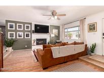 Inviting living room features a white brick fireplace, TV, fan, neutral walls, and a cozy, comfortable brown sofa at 5031 W Grandview Rd, Glendale, AZ 85306