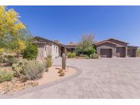 Charming desert home featuring mature landscaping, neutral colors, and a spacious paver driveway at 8555 E Tecolote Cir, Scottsdale, AZ 85266