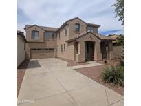 Two-story home with neutral-toned exterior, desert landscaping, and wide driveway leading to a two-car garage at 15446 W Jenan Dr, Surprise, AZ 85379