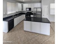 Modern kitchen with granite countertops, stainless steel appliances, and white cabinets at 15446 W Jenan Dr, Surprise, AZ 85379