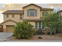 Charming two-story home featuring desert landscaping, a tile roof, blue shutters, and a tan stucco exterior at 42160 W Arvada Ct, Maricopa, AZ 85138