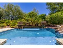 A pristine pool with tile detail, potted plants and privacy landscaping offers a backyard oasis at 30135 N 129Th Gln, Peoria, AZ 85383
