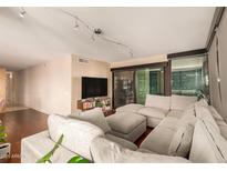 Spacious living room featuring a large sectional sofa, wood floors, and sliding glass doors to the outside at 4808 N 24Th St # 204, Phoenix, AZ 85016