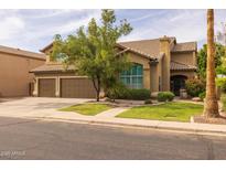 Charming two-story home featuring a three-car garage, manicured lawn, and mature tree, creating a welcoming curb appeal at 9708 E Pampa Ave, Mesa, AZ 85212