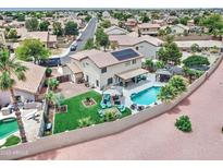 A charming home boasts a backyard oasis with a pristine pool, lush green lawn, and cozy seating, perfect for outdoor relaxation at 16197 N 157Th Ave, Surprise, AZ 85374